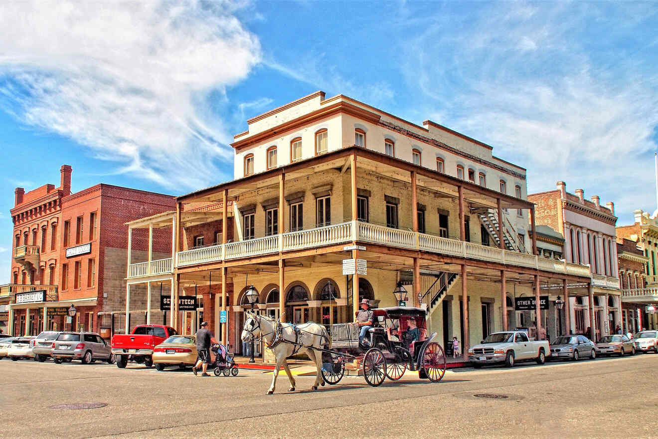 horse carriage on a street in front of a building with parked cars in front of it